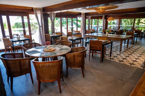 a restaurant with tables and chairs and windows at Wyndham Ilhabela Casa Di Sirena in Ilhabela