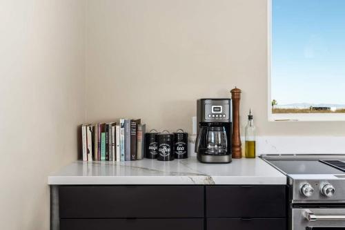 a kitchen counter with a coffee maker and books at Shangrila By The Cohost Company in Joshua Tree