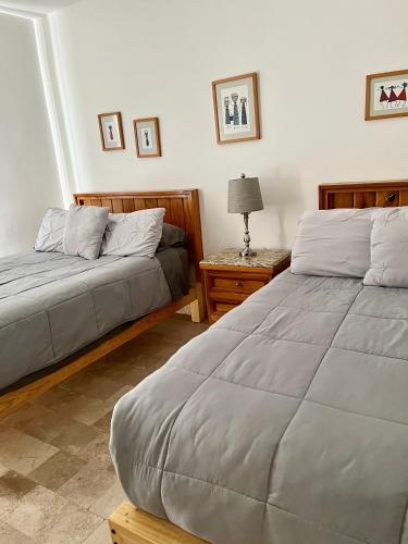 a bedroom with two beds and a table with a lamp at Fantástico departamento en San Miguel de Allende in San Miguel de Allende