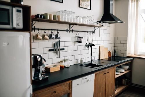 a kitchen with a black counter and white tiles at Horalka Apartments in Jáchymov