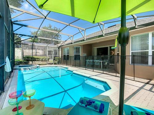 an indoor swimming pool with an umbrella and an outdoor patio at WH7742CS - Newly renovated villa in Windsor Hills in Orlando