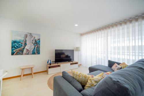 a living room with a blue couch and a tv at Apartamento Lux 1882 in Figueira da Foz