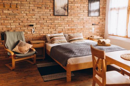 a bedroom with a bed and a chair and a brick wall at Villa Hubertus in Srebrna Góra