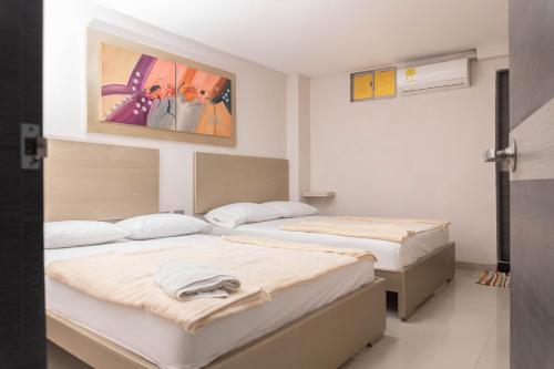 two beds in a room with a painting on the wall at HOTEL DASANTO HD in Barranquilla