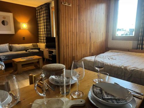 Cette chambre comprend une table avec des verres à vin et un lit. dans l'établissement Résidence Pierres Plates - Les Pierres Plates 4 - Joli studio chaleureux MAE-1871, à Valmorel
