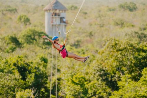 a woman flying through the air on a zip line at Hotel Casa Tortuga Tulum - Cenotes Park Inclusive in Tulum