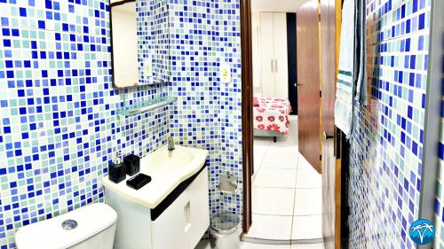 a bathroom with a sink and a toilet and blue tiles at Vacanze - Jardim Tropical in Maceió