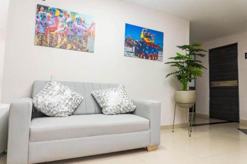 a living room with a couch and paintings on the wall at HOTEL DASANTO HD in Barranquilla
