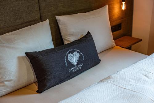 a black pillow sitting on a bed with white pillows at Jaggling Appartements in Sankt Ulrich am Pillersee