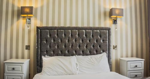 a bed with a black headboard and two night stands at The Pier Hotel in Eastbourne
