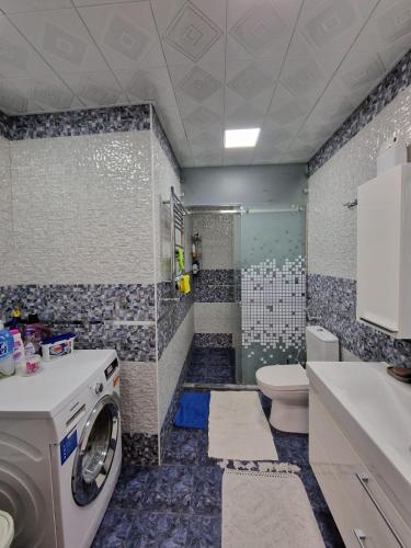 uma máquina de lavar roupa em um banheiro com vaso sanitário em Gamma em Baku