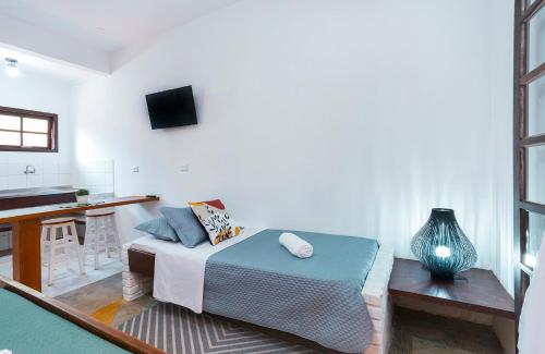 a bedroom with a bed and a kitchen with a table at Pousada Aysú Maresias in Maresias