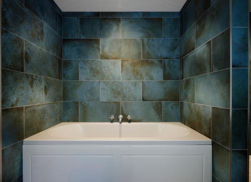 a bath tub in a bathroom with blue tiles at Millslade Country House in Lynton
