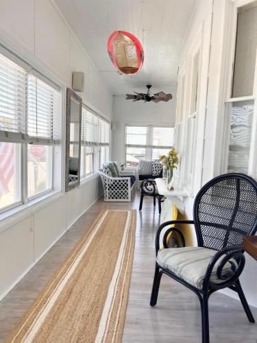 a living room with chairs and a table and windows at Windward at the Beach in Beach Haven