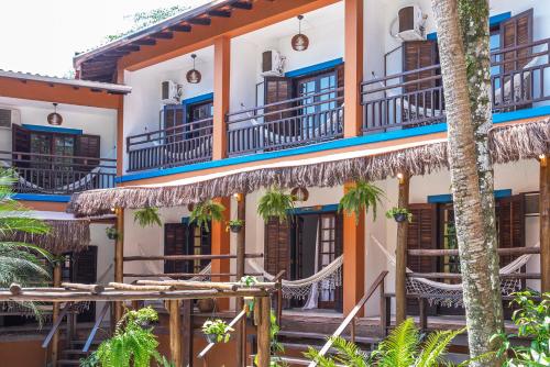 a building with balconies and tables and palm trees at Pousada Aysú Maresias in Maresias