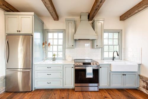 a kitchen with white cabinets and a stainless steel refrigerator at The Mohawk Valley House - 4 suite boutique hotel renamed in Bellmead