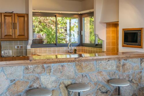 une cuisine avec un comptoir en pierre avec des tabourets dans l'établissement Domaine Kalliste Porto Vecchio, à Porto-Vecchio