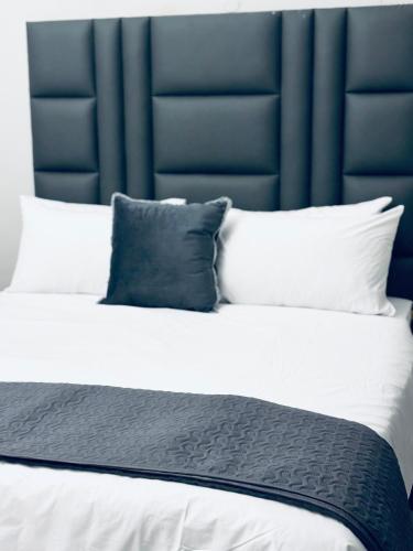 a large bed with a blue headboard and two pillows at Stay-Tiah Whyte Room in Durban