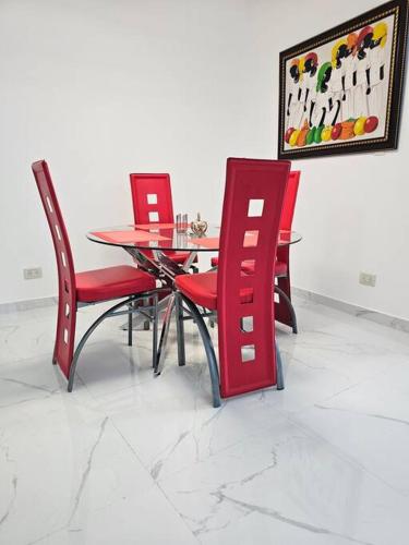 a dining room with red chairs and a table at vista a toda la ciudad y montaña in San Felipe de Puerto Plata