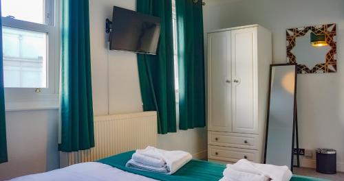 a bedroom with green curtains and a bed and a mirror at The Pier Hotel in Eastbourne