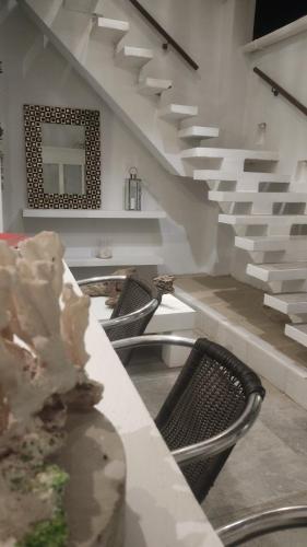 a room with chairs and a table and stairs at Rincón del mar Veleros Hotel in San Onofre