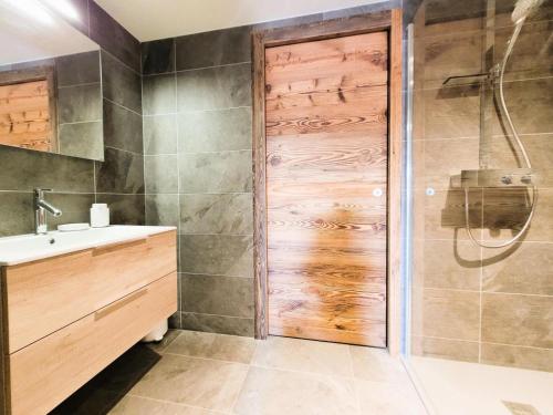La salle de bains est pourvue d'une douche et d'une porte en bois. dans l'établissement Résidence Le Stella - Magnifique appartement haut de gamme MAE-0911, aux Gets