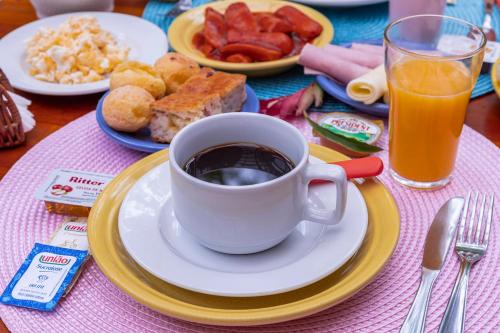 a table with a cup of coffee and a plate of food at Pousada Aysú Maresias in Maresias