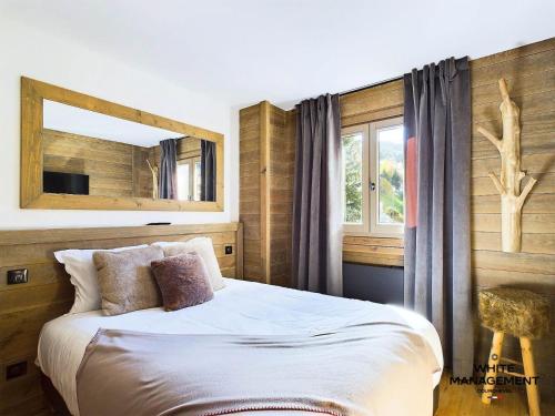 a bedroom with a bed with a mirror and a window at Chalets Le Cepe - Chalet familial moderne à Courchevel Moriond MAE-1951 in Courchevel