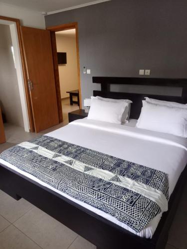 ein großes Bett mit weißen Laken und Kissen in einem Zimmer in der Unterkunft Lodje in Douala