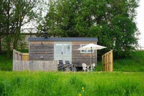 a small cabin with an umbrella and chairs in a field at Jasmine Hut in Bristol