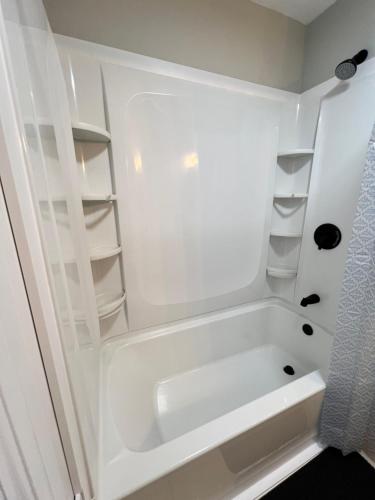 a white bathroom with a tub and shelves at Holyoke House Oasis - Calm Trips in Holyoke