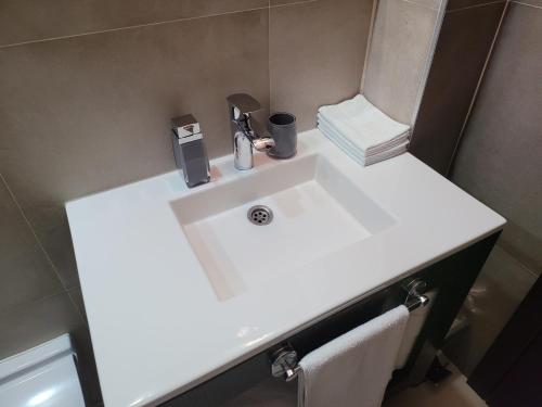 - un lavabo blanc dans la salle de bains avec un distributeur de savon dans l'établissement Nomakop5, à Kopaonik