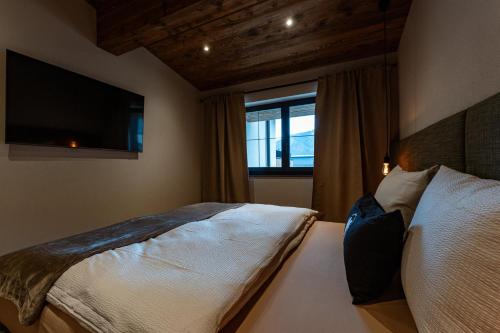 a bedroom with a bed with a tv and a window at Jaggling Appartements in Sankt Ulrich am Pillersee