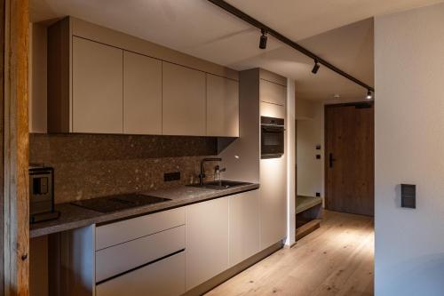 a kitchen with white cabinets and a wooden floor at Jaggling Appartements in Sankt Ulrich am Pillersee