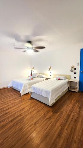 a bedroom with two beds and a ceiling fan at La Puesta del Sol B&B in Carrillo