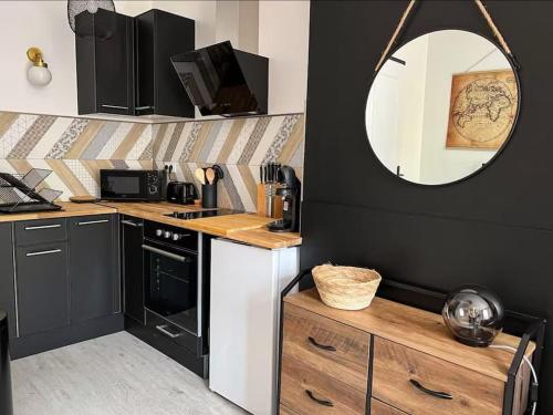 une cuisine avec des placards noirs, un miroir et un comptoir dans l'établissement Appartement Le Petit Galet, au Havre