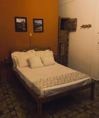 a bedroom with a bed with white sheets and pillows at Trem de Pouso Rustic Guest House in Tiradentes
