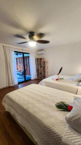 a bedroom with two beds and a ceiling fan at La Puesta del Sol B&B in Carrillo