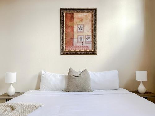 a bed with white sheets and a picture on the wall at Sleepover 2BD 1BA Condos Downtown Springfield in Springfield