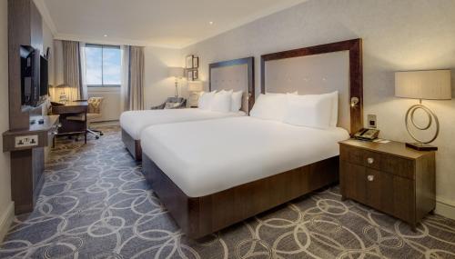 a large hotel room with two beds and a desk at Glasgow Grosvenor Hotel in Glasgow