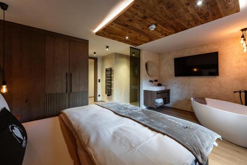 a bedroom with a tub and a bed and a television at Jaggling Appartements in Sankt Ulrich am Pillersee