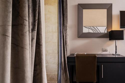 a room with a desk and a mirror and curtains at De Stefano Palace Luxury Hotel in Ragusa
