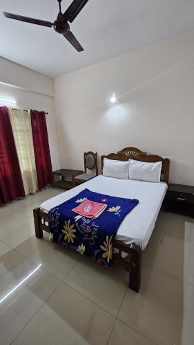 a bedroom with a bed with a blue blanket at Rak palace inn in Ayūr