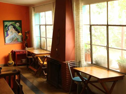 a room with a fireplace and two tables and windows at Hostería Villa Luz Habitación 1 in San Marcos Sierras