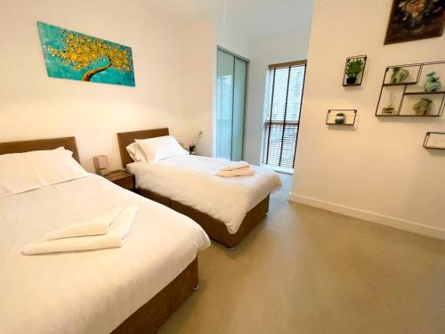 ケンブリッジにあるCentral Luxury Peaceful Home With Driveway Parking - Cambridge Homehostのベッドが2つあり、壁に絵が飾られている部屋