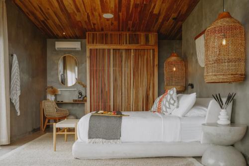 a bedroom with a white bed and a chair at Surf Synergy All-Inclusive Surf and Wellness Retreat in Jacó