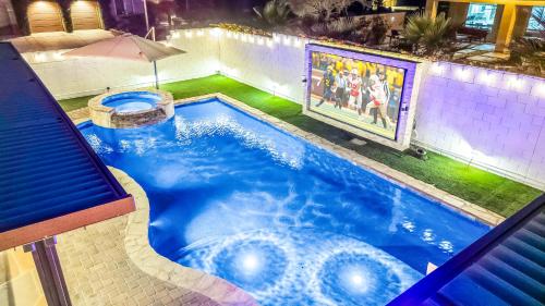an indoor swimming pool with an umbrella and a swimming pool at Hollywood Hideaway with 158" Poolside TV and 2 Arcades in Indio