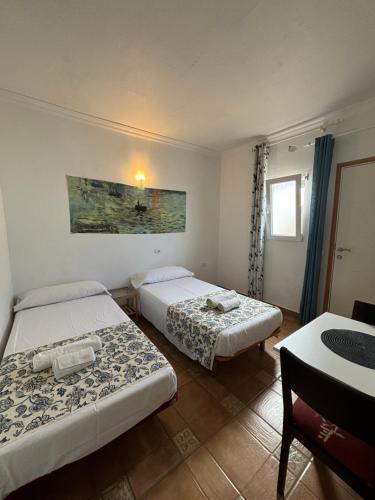 a hotel room with two beds and a table at Apartamentos y Habitaciones Villa Marina in La Caleta