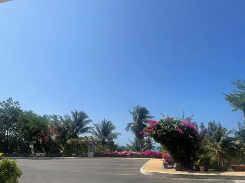 a parking lot with pink flowers and palm trees at Hotel,Căn Hộ Mũi Né Sea link in Phan Thiet