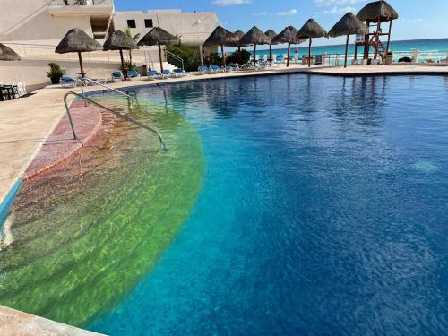 a large swimming pool with blue water and umbrellas at Condominio Privado Villas Marlin Zona Hotelera Cancun in Cancún